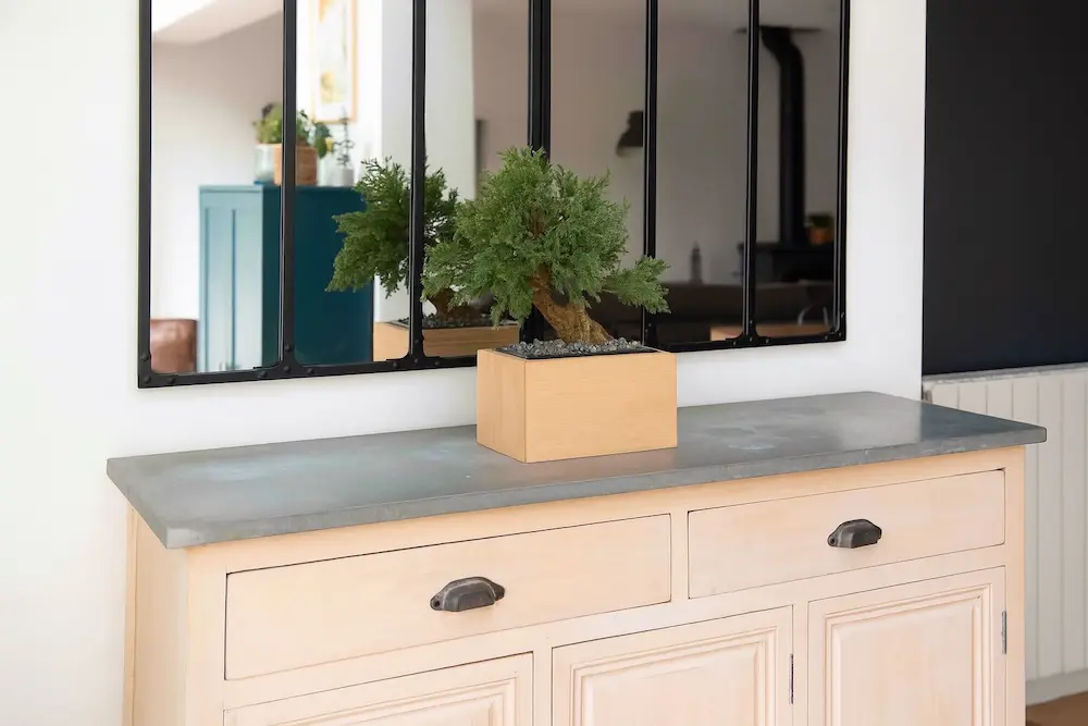 Urne Bonsaï Juniperus en hêtre avec bonsaï artificiel, présentée dans un intérieur lumineux.