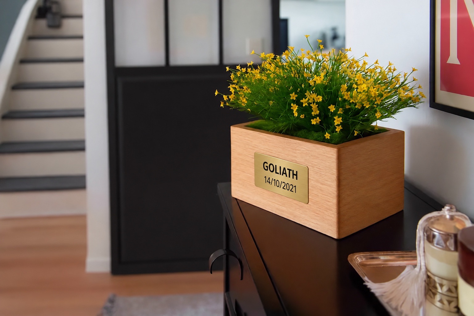 Urne Marguerite Jaune avec plaque personnalisée portant le nom GOLIATH et la date 14/10/2021, dans une entrée lumineuse.