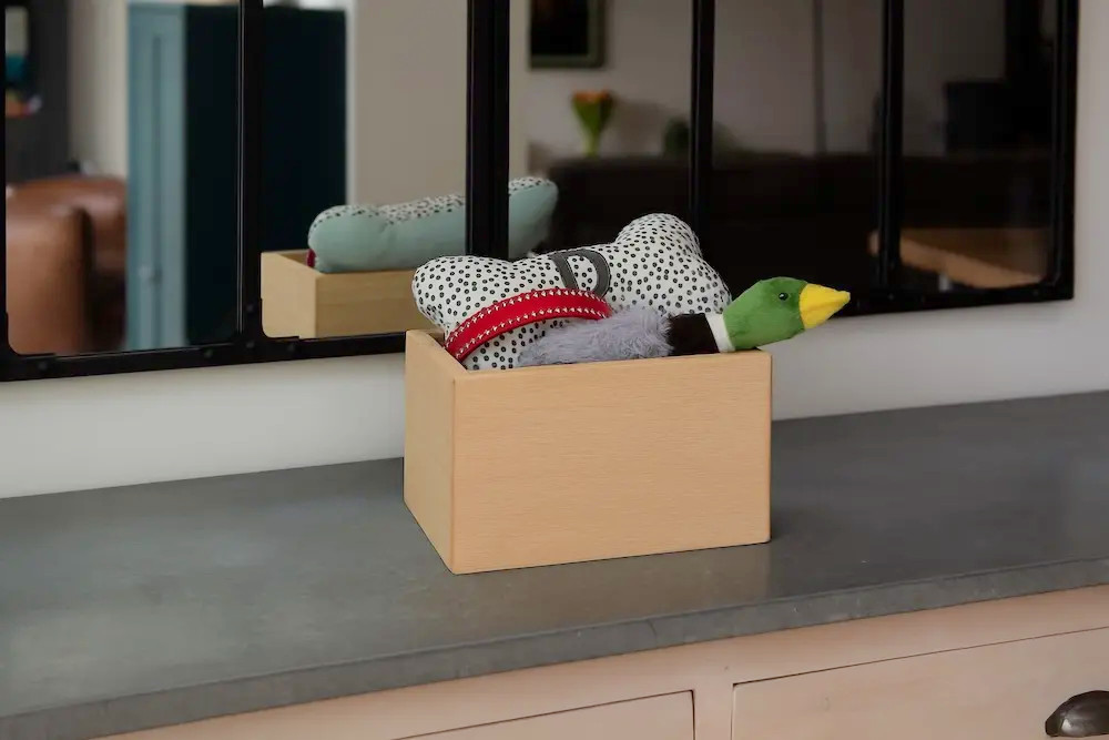 Urne Trésor PT en hêtre contenant des objets souvenirs, présentée dans un intérieur.